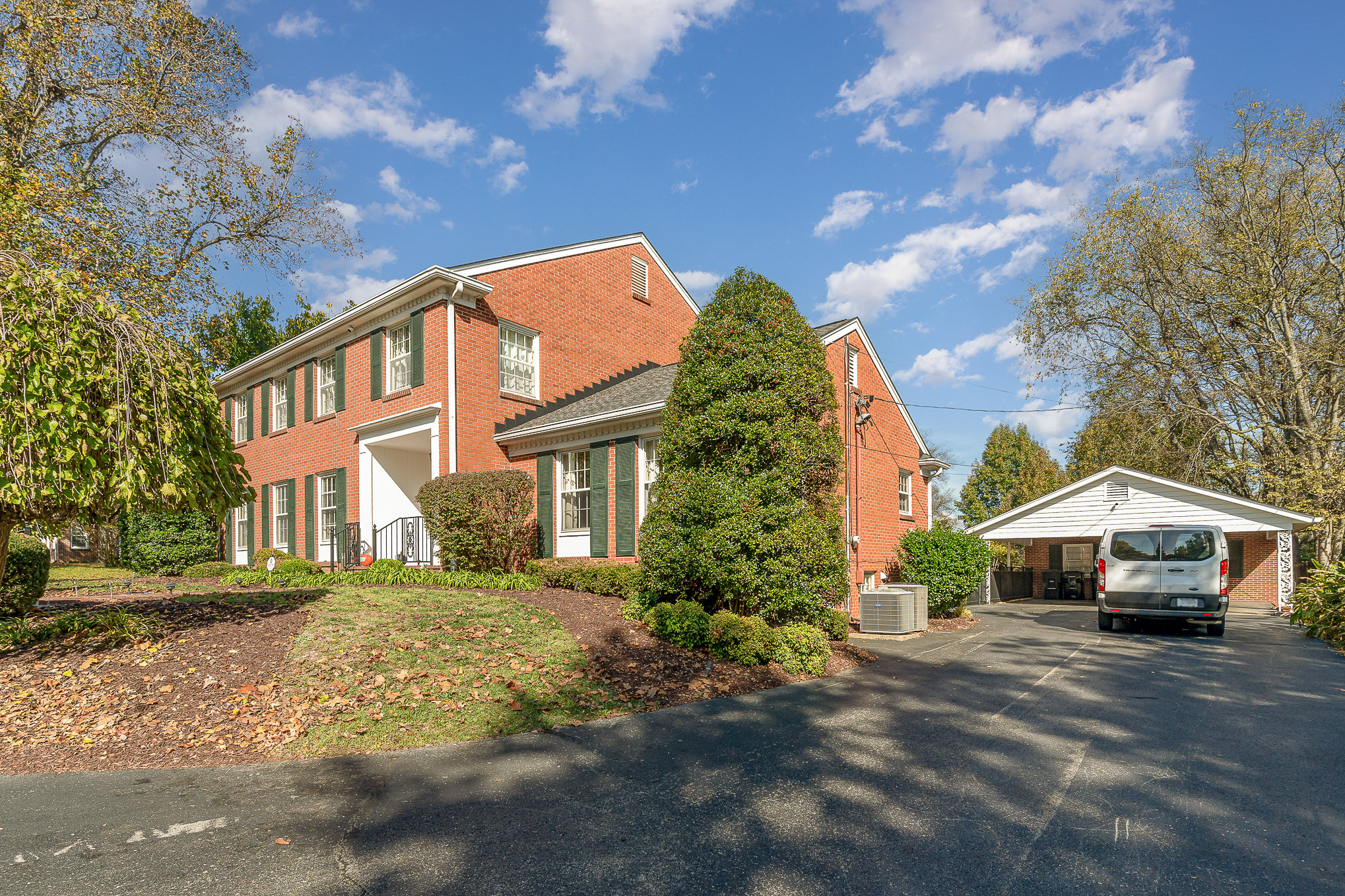 004_file_994 | Nashville Mental Health Brick house with green shutters, van in carport. Real estate home exterior, residential architecture under blue sky.