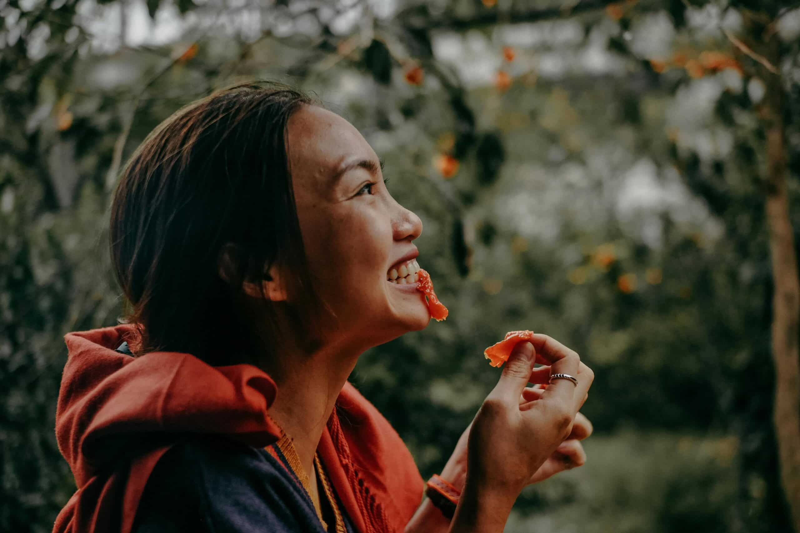 woman smiling while eating food from tree