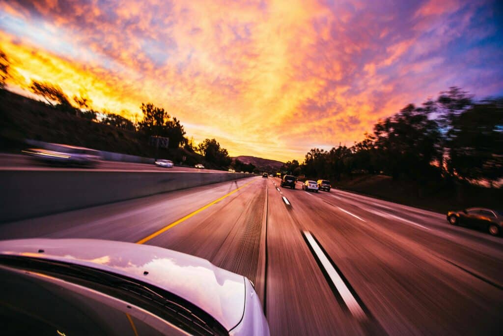 person driving on highway in sunset