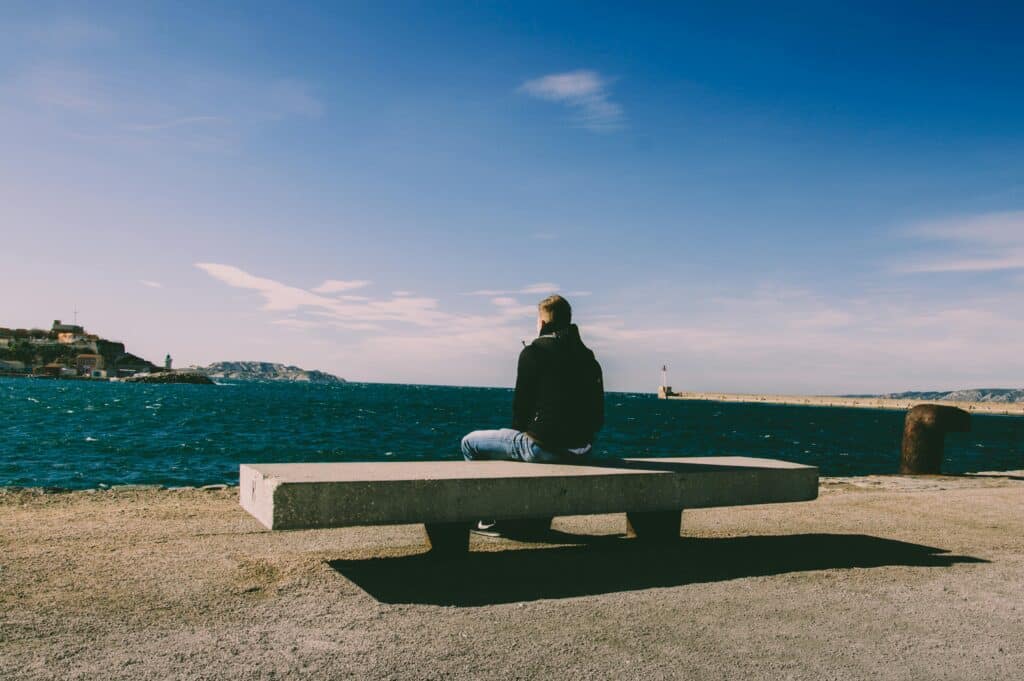 person sitting on bench looking over lake