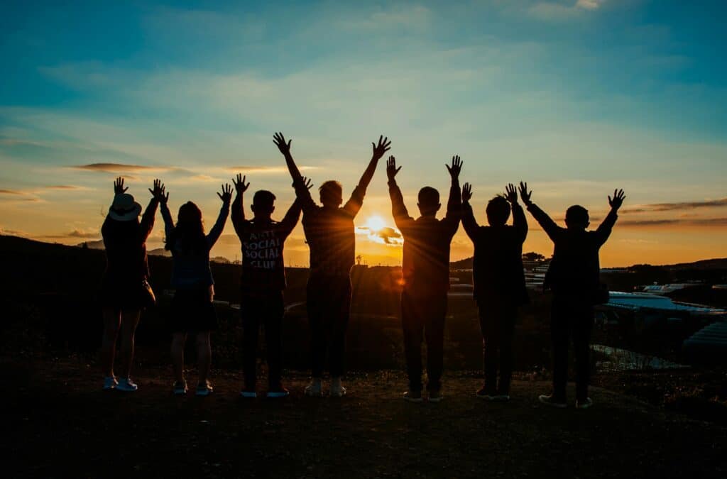 group of people celebrating in front of sunset