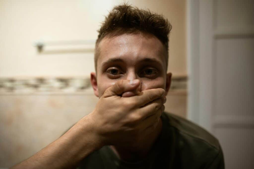 young man's mouth being covered by hand