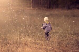 child walking through grass field