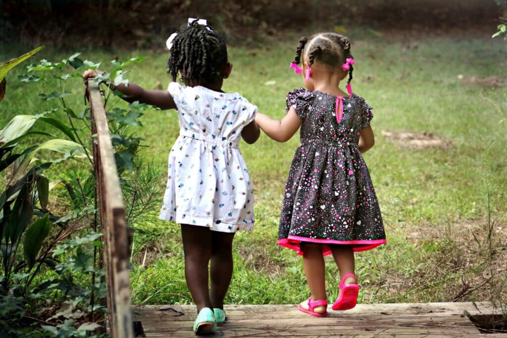 two young kids holding hands and walking