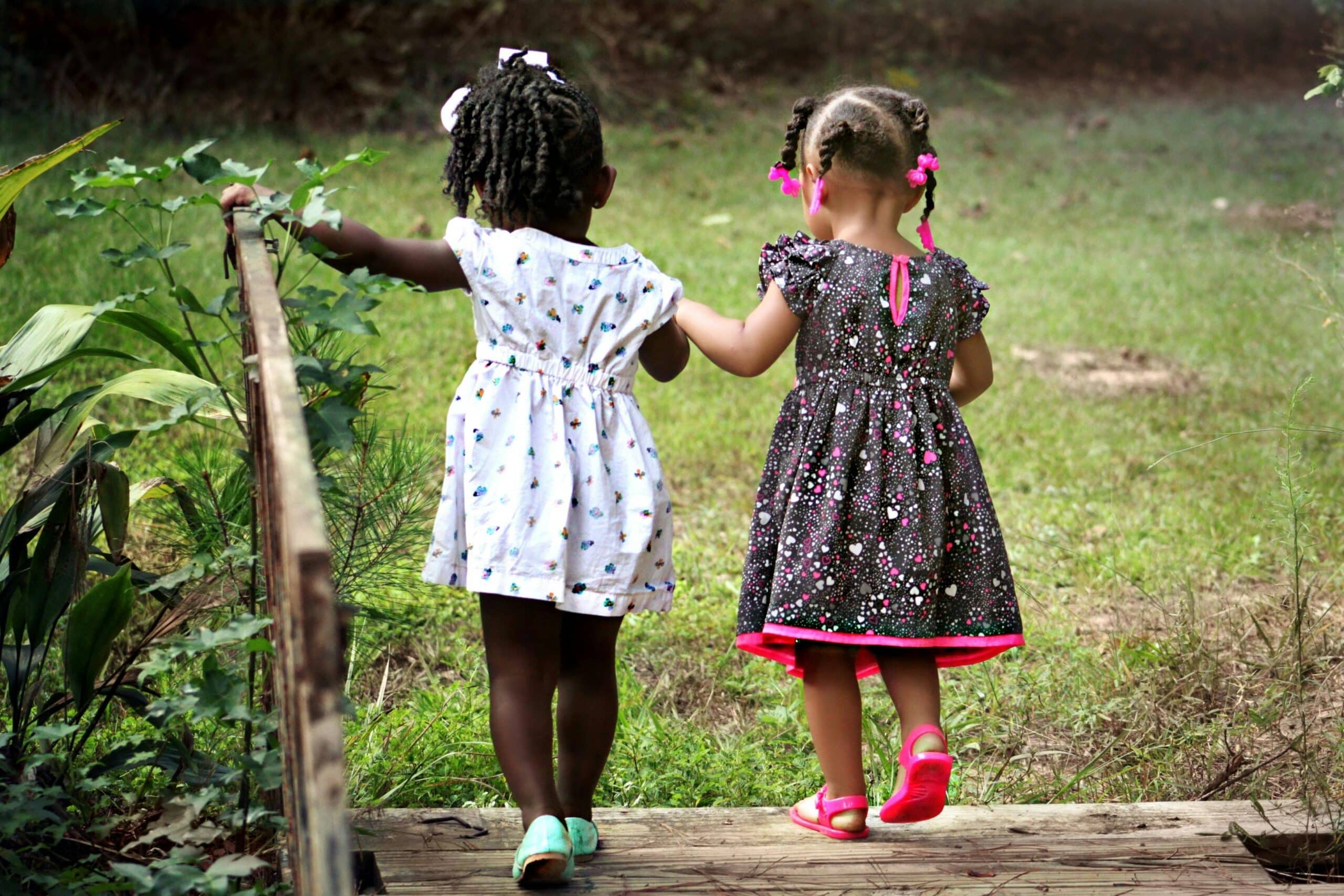 two young kids holding hands and walking