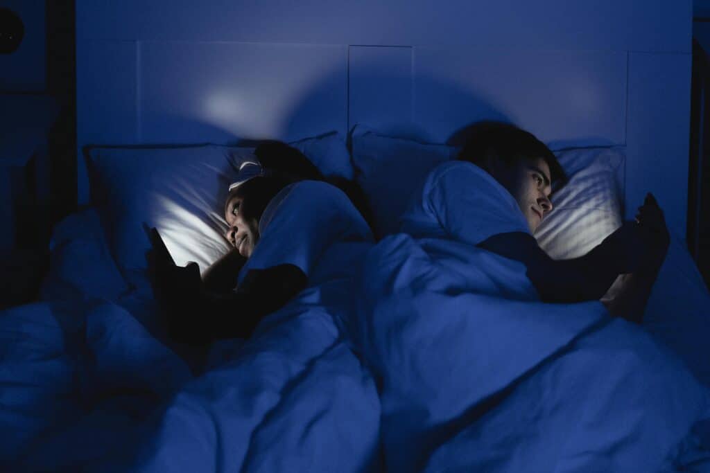 people looking at a screen while in bed