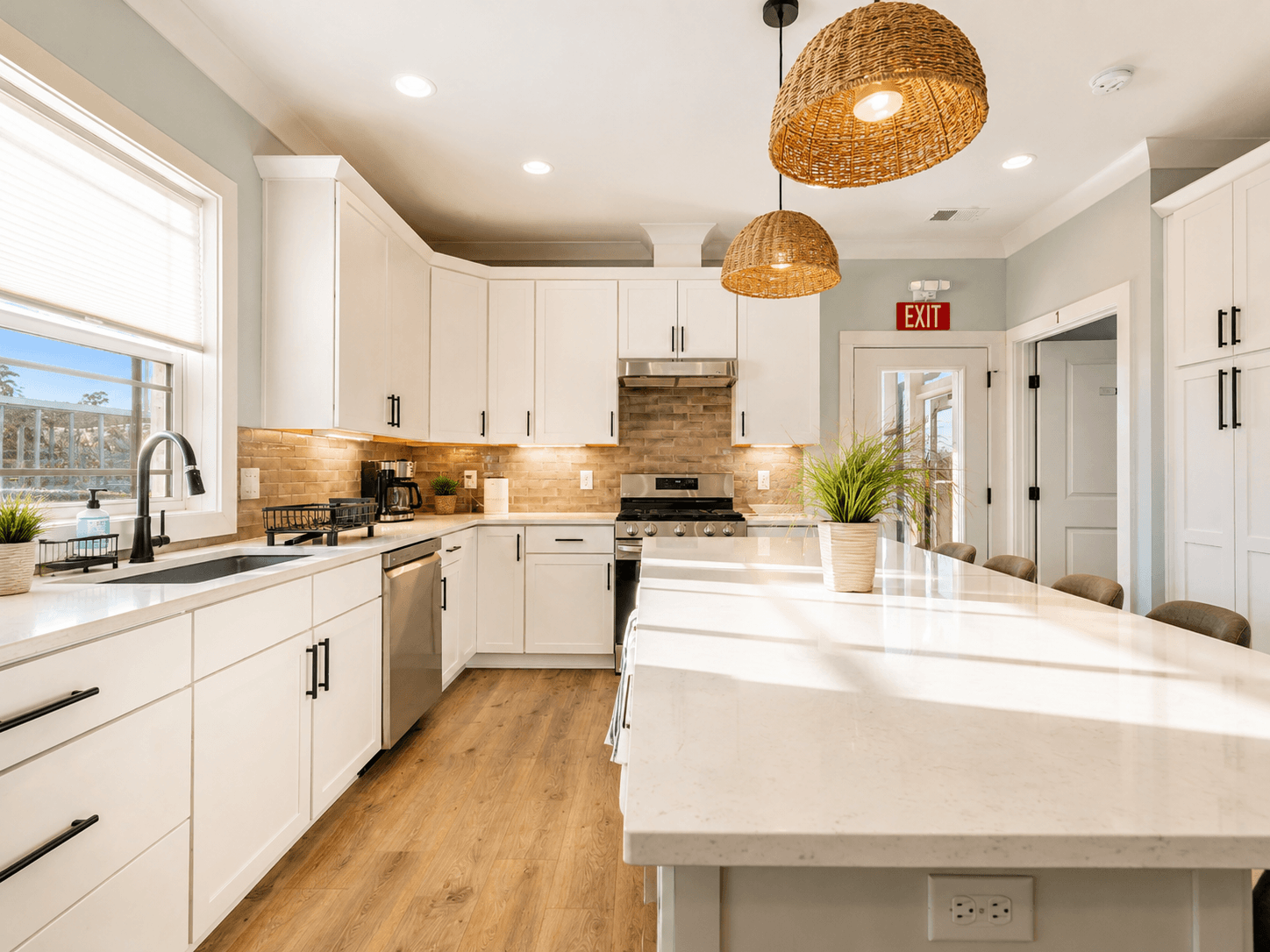 Modern kitchen with white cabinets, stainless appliances, and a large island under woven pendant lights.